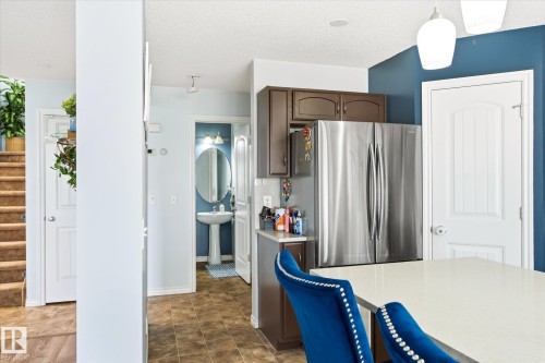 Kitchen area featuring a stainless steel French door refrigerator, brown cabinetry, and a light-colored countertop - 1744 61 Street, Edmonton, AB 