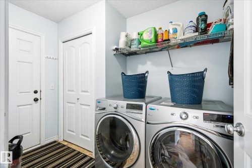 Laundry area featuring a side-by-side washer and dryer set, wire shelving, and light blue wall paint - 1744 61 Street, Edmonton, AB 