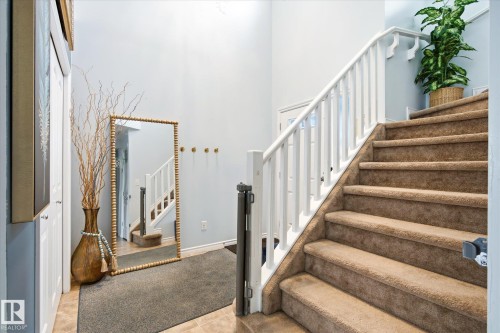 Two-story entryway featuring a light blue wall color, white painted staircase railings, and carpeted stairs - 1744 61 Street, Edmonton, AB 