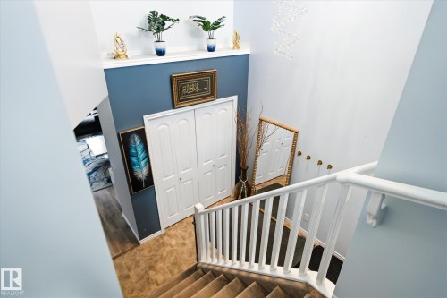 Stairwell featuring white railings, carpeted treads, and a built-in shelf - 1744 61 Street, Edmonton, AB 