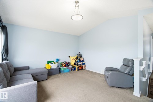 Carpeted interior space featuring light blue walls and a vaulted ceiling - 1744 61 Street, Edmonton, AB 