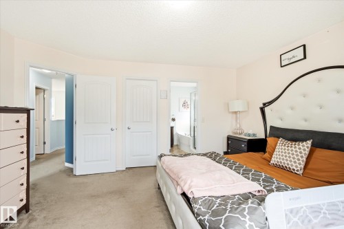 Carpeted room with a vaulted ceiling, white interior doors, and a partial view of an adjacent bathroom with a built-in tub - 1744 61 Street, Edmonton, AB 