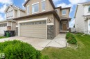 Contemporary exterior featuring light brown siding, stone accents, and a double garage with window inserts - 1744 61 Street, Edmonton, AB 
