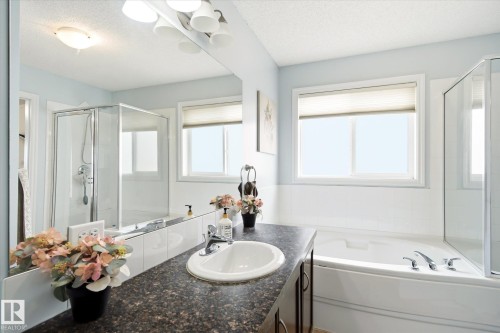 Bathroom featuring a dark speckled countertop, white undermount sink, chrome faucet, and a large mirror - 1744 61 Street, Edmonton, AB 