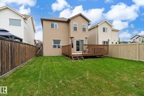Expansive grassy backyard featuring a wooden deck, sliding glass door access, and full perimeter wood fencing - 1744 61 Street, Edmonton, AB 