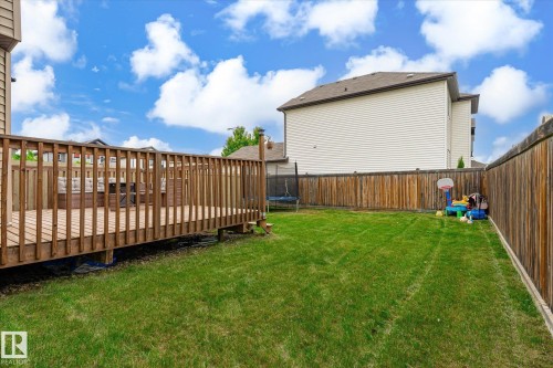 Expansive backyard featuring a wood deck with railing, a grass lawn, and wood privacy fencing - 1744 61 Street, Edmonton, AB 