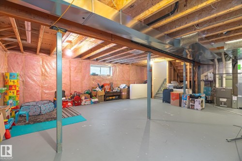Unfinished basement featuring exposed wood joists, a painted concrete floor, and insulated walls - 1744 61 Street, Edmonton, AB 