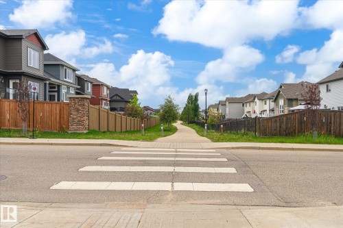 Paved pedestrian pathway bordered by residential properties featuring varied architectural styles and wood privacy fencing - 1744 61 Street, Edmonton, AB 