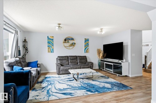 Spacious living area featuring wood-finish flooring, light-toned walls, and recessed lighting - 1744 61 Street, Edmonton, AB 
