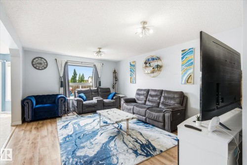 Open-concept living area featuring wood-finish flooring, light-toned walls, and a large window providing outdoor views - 1744 61 Street, Edmonton, AB 