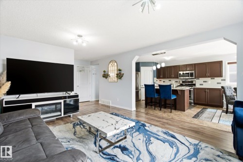 Living area with wood-finish flooring, featuring an entertainment console with a built-in electric fireplace - 1744 61 Street, Edmonton, AB 