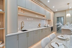 Contemporary kitchen featuring integrated lighting, light-toned cabinetry, and a gold-finish faucet - 