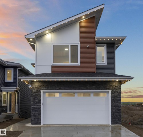 Contemporary exterior featuring a prominent garage, stone veneer siding, and a multi-pitched roofline - 3305 Chickadee Drive, Edmonton, AB 