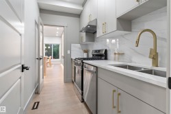 Galley kitchen with light gray cabinetry, stainless steel appliances, a double basin sink, and a gold-finish faucet - 