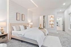 Expansive bedroom featuring light grey carpet, white shiplap accent wall, recessed lighting, and a built-in display niche with wooden shelving - 