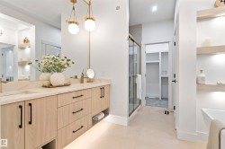 Dual vanity featuring wood-finish cabinetry, light-toned countertops, and gold-finish hardware - 
