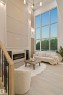 Two-story living area featuring a full-height window wall, light wood-finish flooring, a built-in electric fireplace, recessed lighting, and an overhead chandelier - 3305 Chickadee Drive, Edmonton, AB 