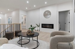 Open-concept living space featuring a linear electric fireplace with shiplap surround, wood-finish flooring, recessed lighting, and a contemporary stair railing with black spindles - 