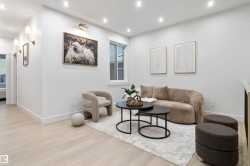 Living area with light wood-finish flooring, recessed lighting, and a window providing natural light - 