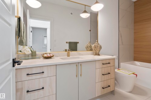 Floating vanity with a light-toned countertop, integrated sink, and gold-finish faucet - 3305 Chickadee Drive, Edmonton, AB 