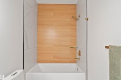 Contemporary tub and shower combination featuring wood-finish wall paneling and large format white tile - 
