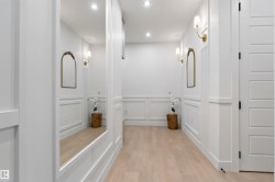 Hallway featuring light wood-finish flooring, recessed lighting, and decorative wall paneling - 