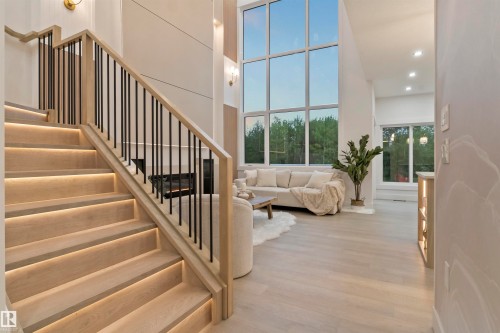 Hardwood staircase with integrated step lighting and black metal balusters - 3305 Chickadee Drive, Edmonton, AB 