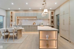 Contemporary kitchen featuring recessed lighting, a central island with integrated shelving, under-cabinet lighting, a built-in refrigerator, and light wood-finish flooring - 