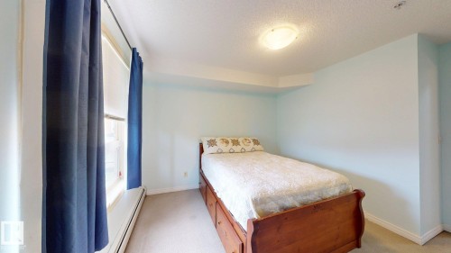 Window with white trim and blue drapes, light blue walls, and a ceiling-mounted light fixture - 209 13908 136, Edmonton, AB 