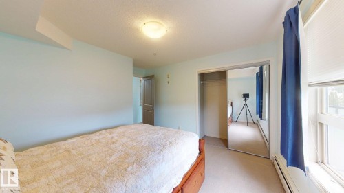 Bedroom featuring light blue walls, carpeted flooring, a flush-mount ceiling light, and a window with blinds - 209 13908 136, Edmonton, AB 