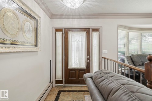 Entryway featuring a wood-paneled door with decorative glass, side-panel windows, and a crystal flush-mount light fixture - 12131 101 Street Nw, Edmonton, AB 