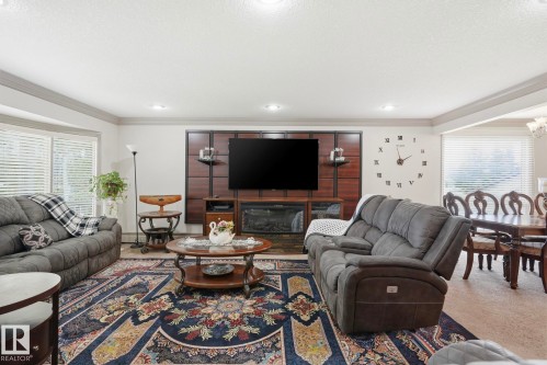 Spacious living area featuring a custom media wall with an integrated fireplace - 12131 101 Street Nw, Edmonton, AB 