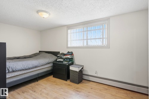 Room featuring wood-finish flooring, white walls, and a ceiling-mounted light fixture - 12131 101 Street Nw, Edmonton, AB 