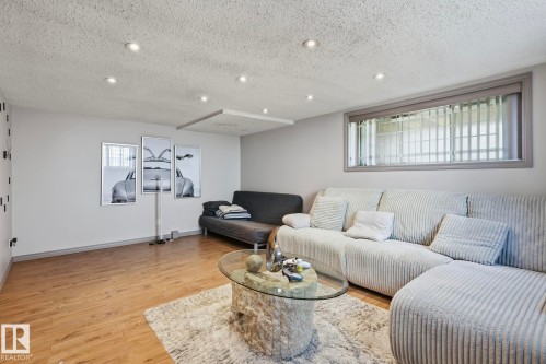 Spacious living area featuring wood-finish flooring, recessed lighting, and a large window with privacy blinds - 12131 101 Street Nw, Edmonton, AB 