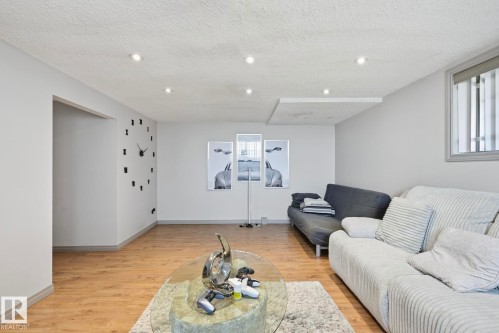 Spacious room featuring wood-finish flooring, recessed lighting, and a white textured ceiling - 12131 101 Street Nw, Edmonton, AB 