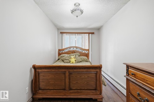 Interior room featuring wood-finish flooring, a window with vertical blinds, white walls, and a ceiling-mounted light fixture - 12131 101 Street Nw, Edmonton, AB 