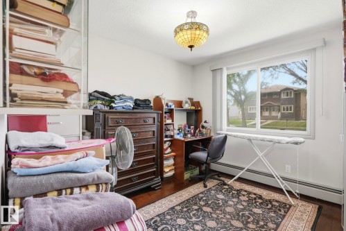 Bright room featuring a large window, dark wood-finish flooring, and a decorative ceiling light fixture - 12131 101 Street Nw, Edmonton, AB 