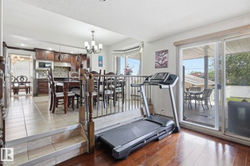 Open-concept living space featuring wood-finish flooring, a patio door, and a multi-level layout - 12131 101 Street Nw, Edmonton, AB 