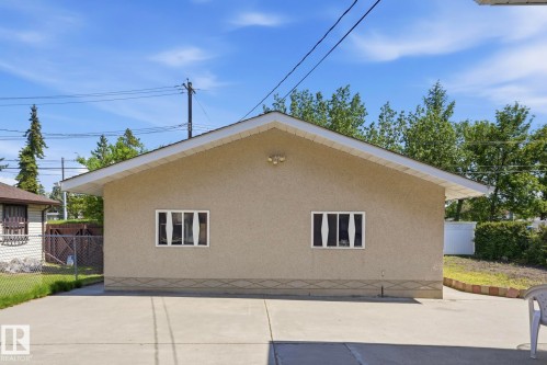 Stucco exterior with a pitched roof, featuring two windows with white frames and vertical blinds - 12131 101 Street Nw, Edmonton, AB 
