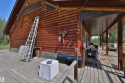 Spacious wood-planked porch extending alongside a log-sided structure with stone veneer detailing - 