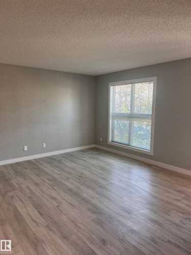 Spacious interior room featuring light gray walls, wood-finish flooring, and white trim - 1313 Chappelle Boulevard, Edmonton, AB 