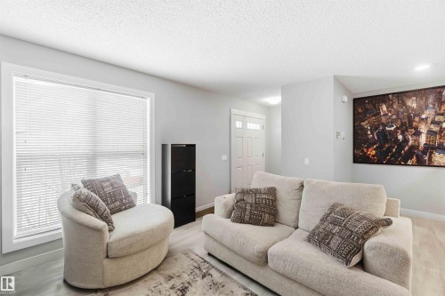 Spacious living area featuring light-toned walls, wood-finish flooring, and a large window with white blinds - 1313 Chappelle Boulevard, Edmonton, AB 