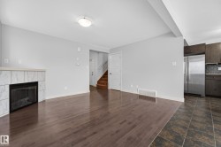 Living area featuring wood-finish flooring and a tiled fireplace - 