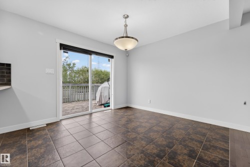Sliding glass doors opening to an outdoor deck, complemented by a contemporary ceiling fixture and tile flooring - 5244 1A Avenue, Edmonton, AB 
