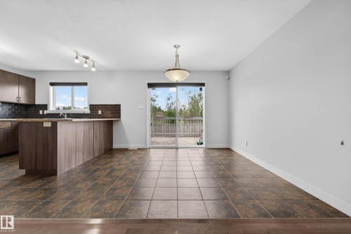 Open-concept kitchen and dining area featuring dark wood-finish cabinetry, a breakfast bar, and a dark tile backsplash - 5244 1A Avenue, Edmonton, AB 