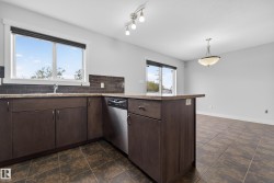 Kitchen featuring dark wood-finish cabinetry, a stainless steel dishwasher, and a breakfast bar - 