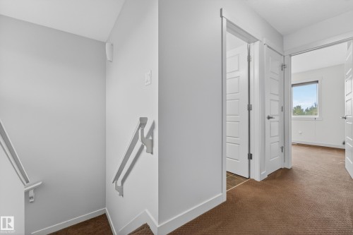 Upper-level hallway featuring brown carpet flooring and white trim - 5244 1A Avenue, Edmonton, AB 