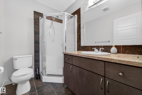 Enclosed glass shower stall complemented by a dark wood-finish vanity with an integrated sink and chrome fixtures - 5244 1A Avenue, Edmonton, AB 