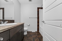 Bathroom featuring a spacious vanity with an integrated sink, dark wood-finish cabinetry, and a stone-look countertop - 