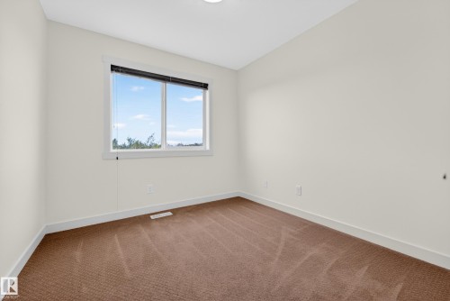 Room featuring neutral painted walls, brown carpet flooring, and white baseboards - 5244 1A Avenue, Edmonton, AB 